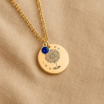 Personalized september carnation and birthstone necklace displayed on a neutral fabric background